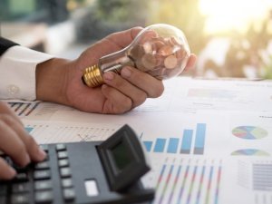 Hand of businessman hold light bulb with coin. Concept of Cost reduction and Reduce energy