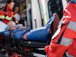 Selective focus of paramedic in uniform carrying stretcher with patient in ambulance ca outdoors