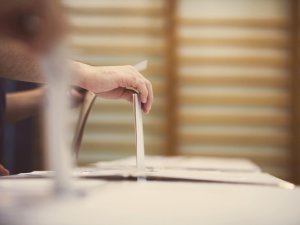 Hand of a person casting a ballot at a polling station during voting.