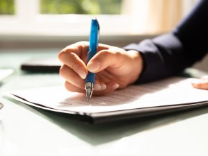 Close-up Of A Businesswoman's Hand Filling Contract Form
