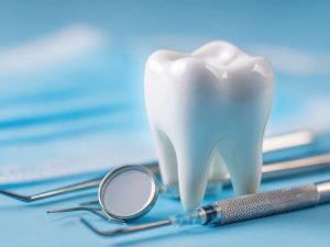 The essential dental tools and a healthy tooth on a blue background.