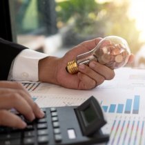 Hand of businessman hold light bulb with coin. Concept of Cost reduction and Reduce energy