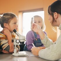 Education, science and test tube with children in classroom for development or learning. Experiment, microscope and sample with teacher speaking to student kids at school for research or study.